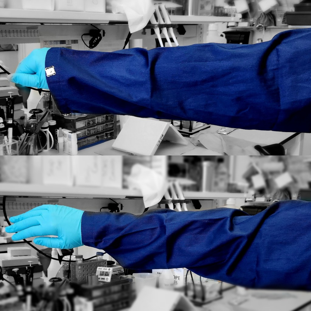 A square image split horizontally in the middle to feature two panels.The background for both panels is a lab bench in black and white that is slightly blurred. In each panel, a navy blue lab coat is on an arm that is extends straight out, away from the body. A light teal glove covers the hand. In the top panel, the lab coat is lose at the wrist. The bottom panel shows the navy lab coat tapered at the wrist.